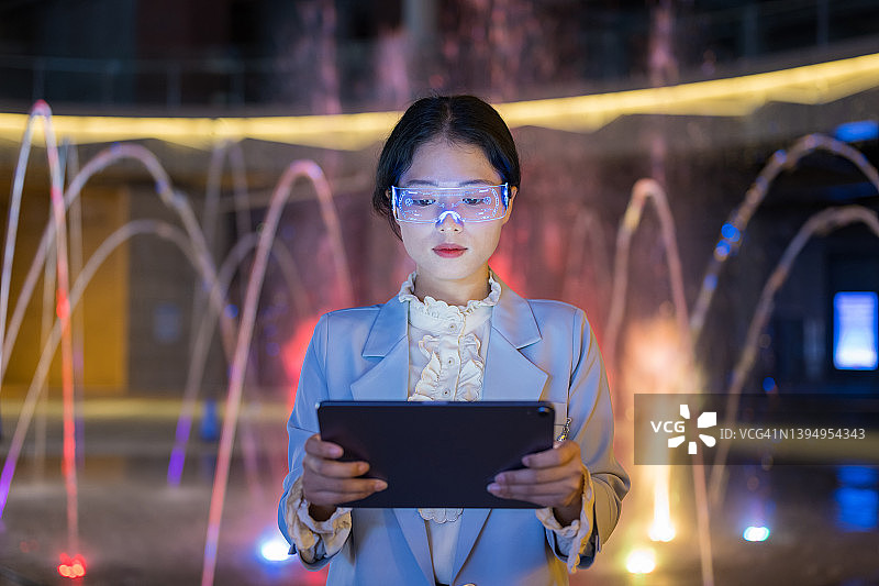 年轻的女商人戴着增强现实眼镜使用平板电脑图片素材
