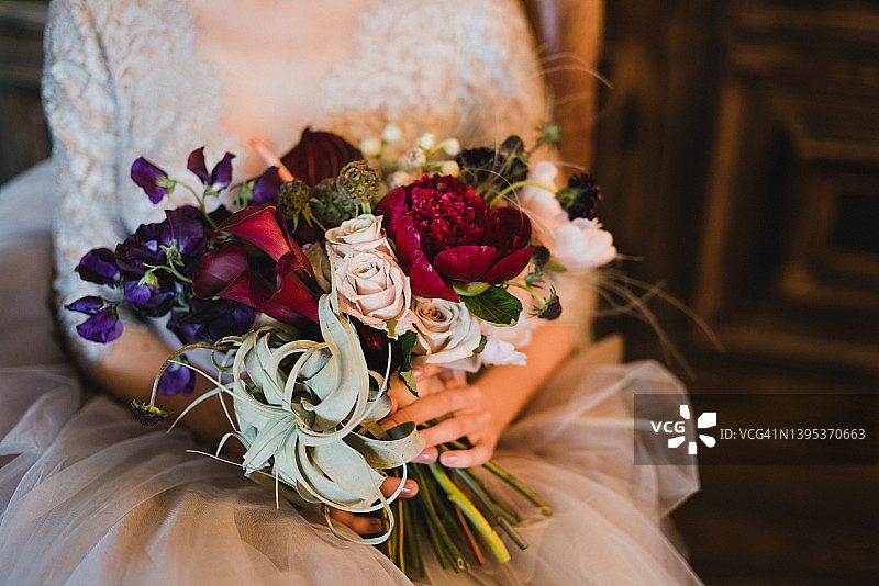 特写的白人新娘持有一个美丽的婚礼花束色彩鲜艳的鲜花在她的手。图片素材