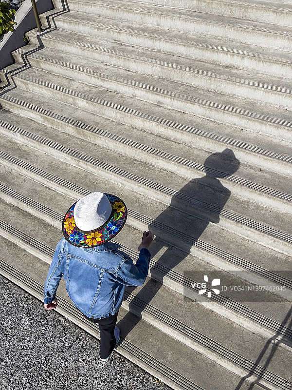 头顶上一个戴着彩色帽子的女人走在外面的楼梯上。图片素材