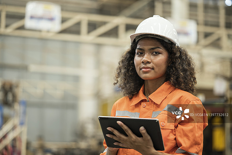 生产过程的监控。一名女性非裔美国工业工程师在领先的制造业工作时手持平板电脑的肖像。她擅长汽车零部件的生产过程控制。图片素材