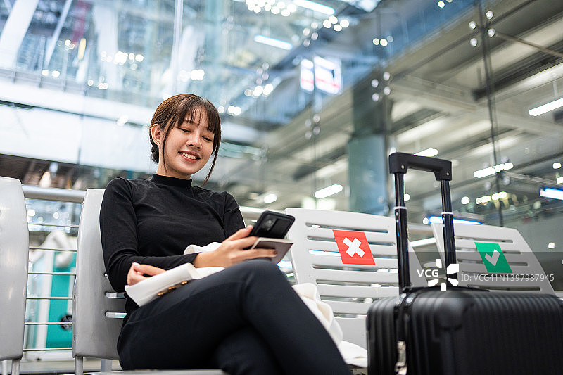 年轻的亚洲女性在机场候机时使用智能手机图片素材