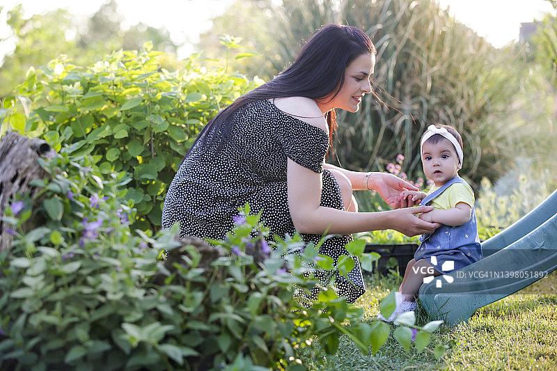 年轻的母亲和她的宝贝女儿在户外享受田园般的夏日。公园里的全家福。图片素材