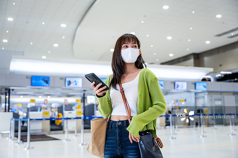 亚洲年轻女子在机场候机楼使用电话图片素材