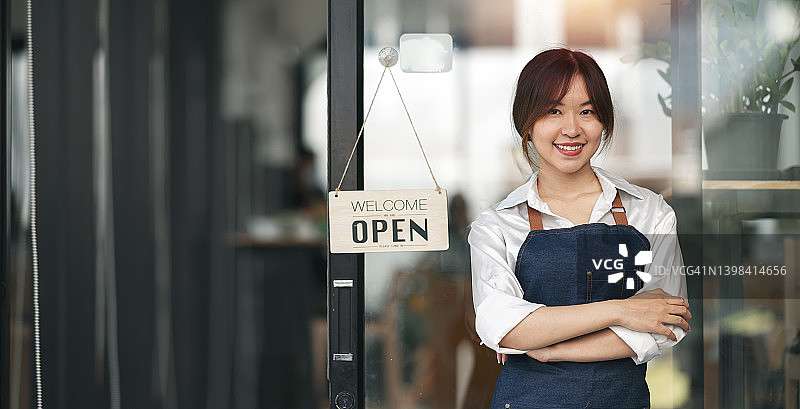 正面的亚洲女商人站在餐厅门口的肖像。图片素材