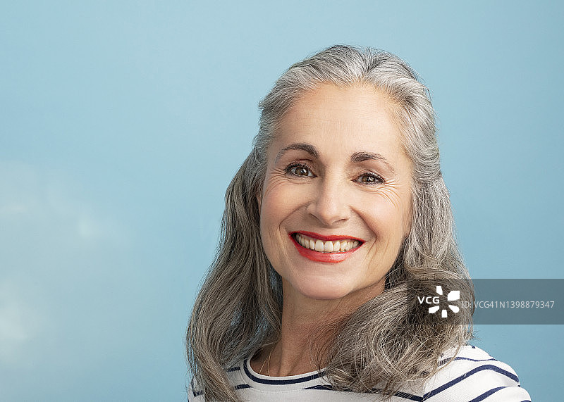 微笑的女人与灰色的头发在蓝色的背景图片素材