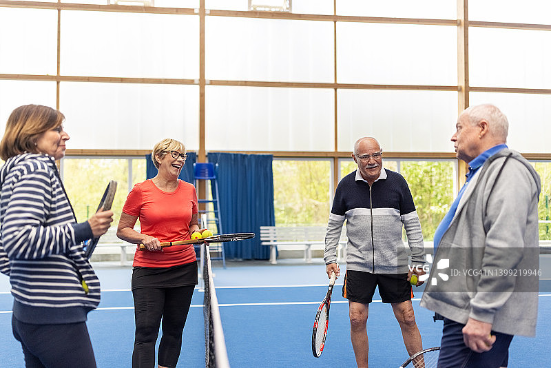 快乐的老年夫妇在室内球场打网球图片素材