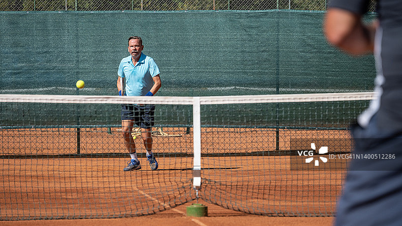 男子在体育中心的户外球场打网球比赛图片素材