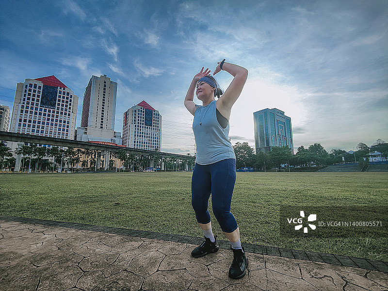 亚洲华人女强人周末早上在公园做热身运动图片素材