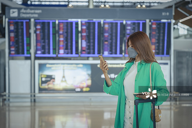 年轻的亚洲女商人在机场旅行时用手机阅读电子邮件。商务旅行的概念。图片素材