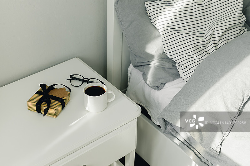 早上的一杯咖啡，眼镜，礼物，在父亲节快乐的床头柜上有黑丝带的礼物。节日的概念图片素材