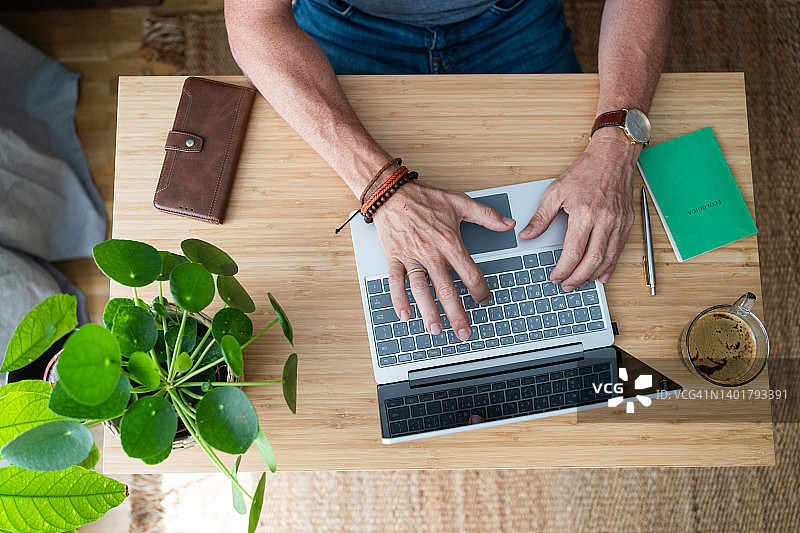 不认识的人的手在键盘上打字在家里的办公室桌上的笔记本电脑图片素材