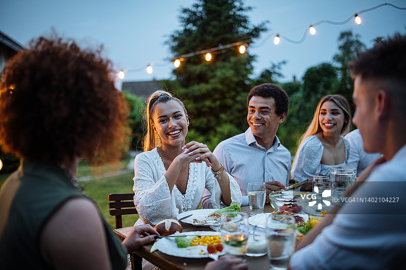 在温暖的夏夜，朋友和家人在户外吃晚餐图片素材