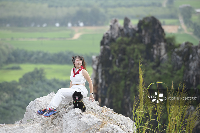 一个年轻的女人和她的狗在山顶上图片素材