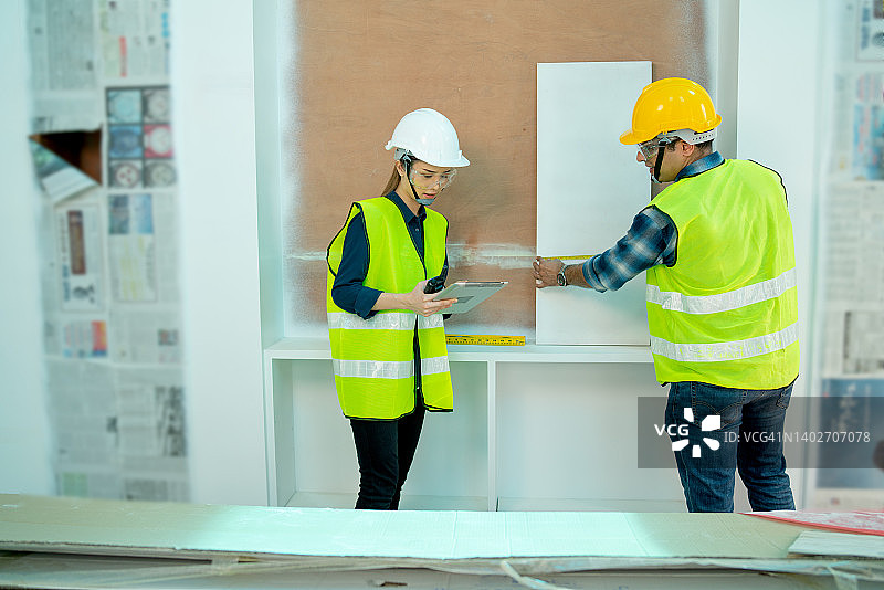 亚洲工程师或经理与印度工人在施工现场用卷尺检查层板的尺寸和位置图片素材