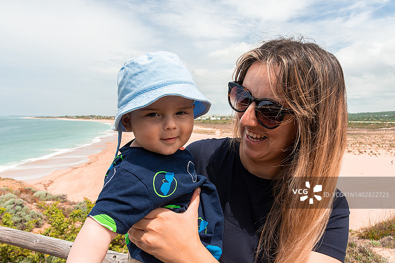 一个快乐的母亲和她的孩子的肖像。背景是海滩。夏天的时间。图片素材