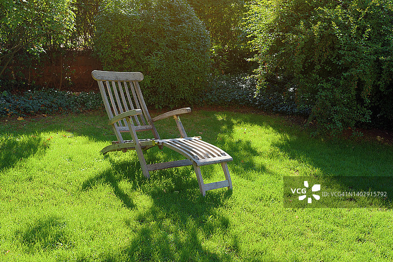 夏天，花园中绿油油的草地上放着一把躺椅图片素材