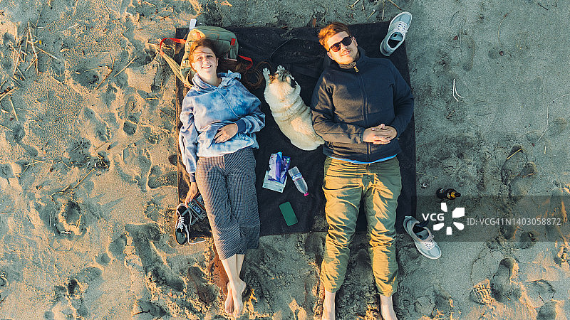 鸟瞰快乐的女性和男性与狗在土耳其海滩享受日落图片素材