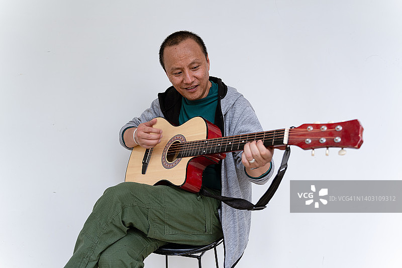 一个正在弹吉他的亚洲中年男子图片素材