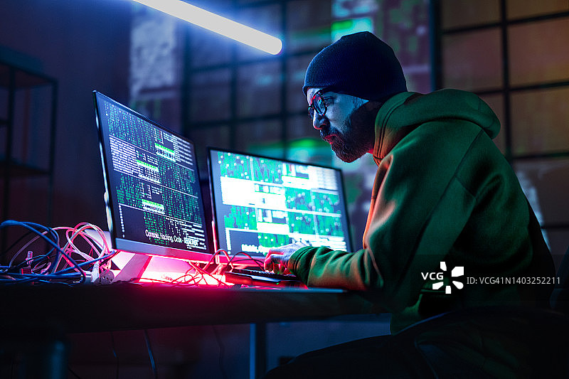 黑客在暗室里操作电脑，侧视图。图片素材