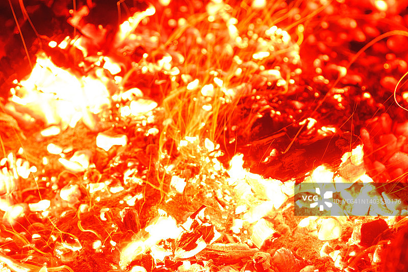 特写镜头的营火明亮燃烧在晚上投掷火花。图片素材