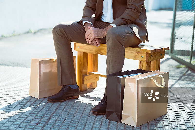 拿着购物袋坐在长椅上的男性顾客图片素材