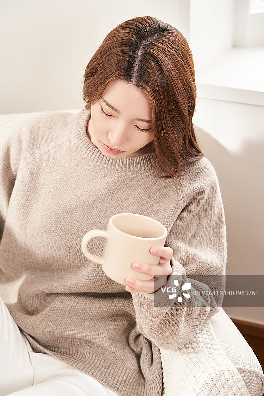 一个女人坐在沙发上喝茶图片素材