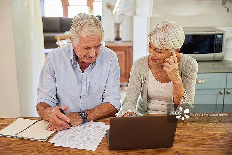 一对老年夫妇使用笔记本电脑查看家庭财务状况图片素材