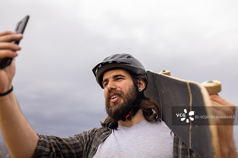 男性滑板者用手机自拍图片素材