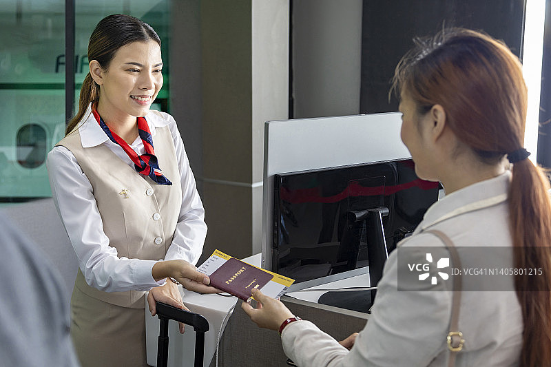 一名亚洲乘客在登机口向航空公司地勤人员出示登机牌，准备登机前的最后检查图片素材