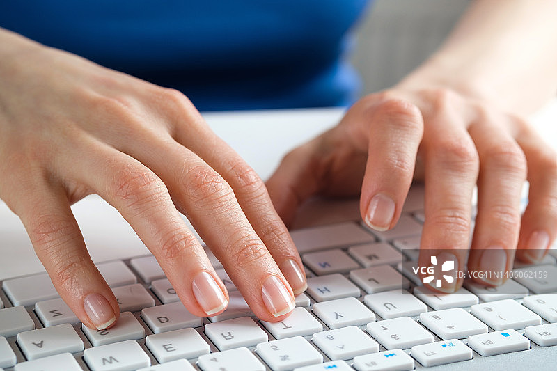 女性用手在电脑或笔记本电脑的键盘上打字。一个女人，坐在办公桌前的办公室职员。商业的概念，自由职业，在家工作。IT支持，网络安全，在线社会支持。网上远程学习。图片素材