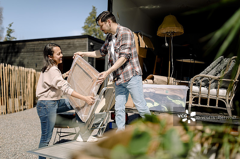 一个男人和一个女人在阳光明媚的日子从卡车上卸下油漆图片素材