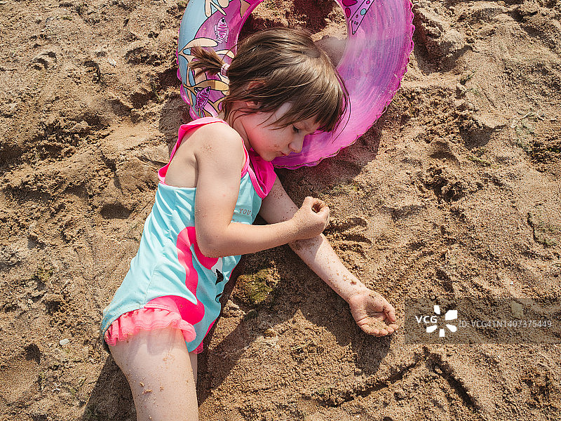 小女孩在沙滩上游泳圈上休息图片素材