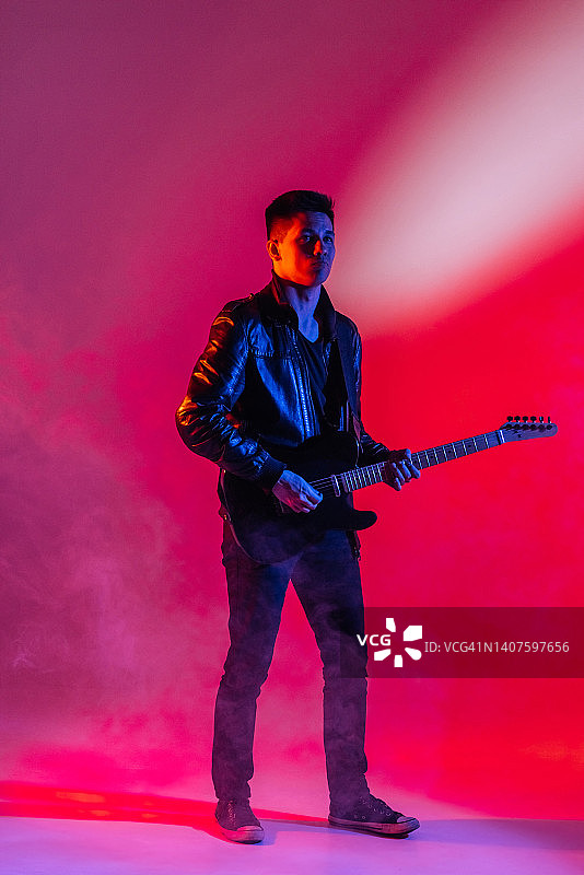 音乐家在霓虹灯下用吉他弹奏一首歌曲图片素材