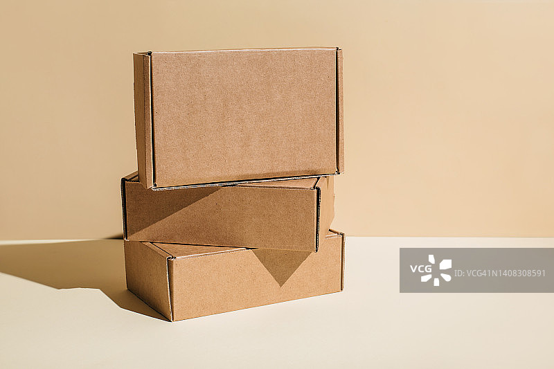 棕色的纸板箱堆叠在米色背景上，复制空间。图片素材