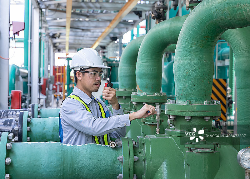 亚洲男性工程师，在工厂从事管道和泵的工作。图片素材
