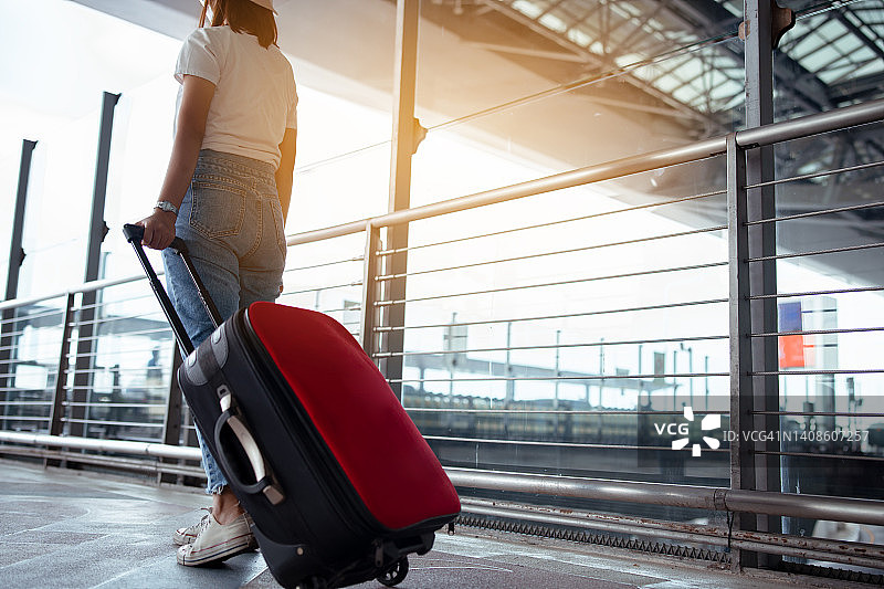 机场概念中的旅行箱旅行者。年轻的女孩带着行李步行，旅客为旅游旅行订机票，在国际假期的假期休息和放松。图片素材