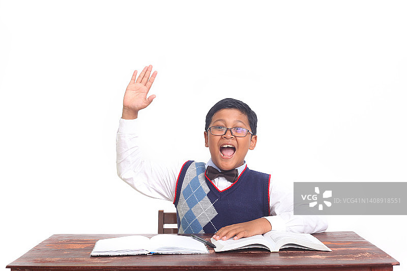 一个自信的亚洲小男孩举手回答问题图片素材