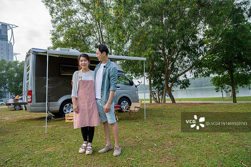 幸福的亚洲华人夫妇站在他们的房车前-露营车旅行系列图片素材
