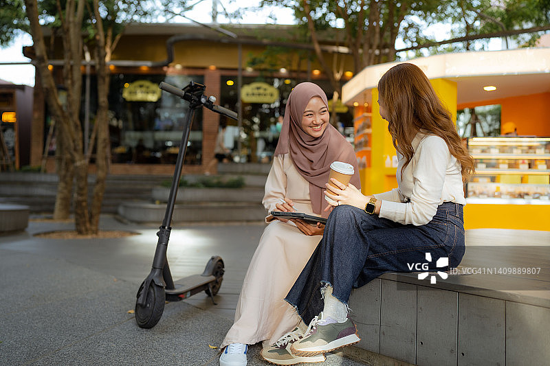 亚洲女商人在公园喝咖啡休息时聊天。图片素材