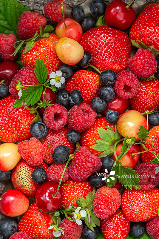 许多不同成熟的浆果，草莓，覆盆子，蓝莓，甜樱桃作为背景纹理。平铺，俯视图图片素材