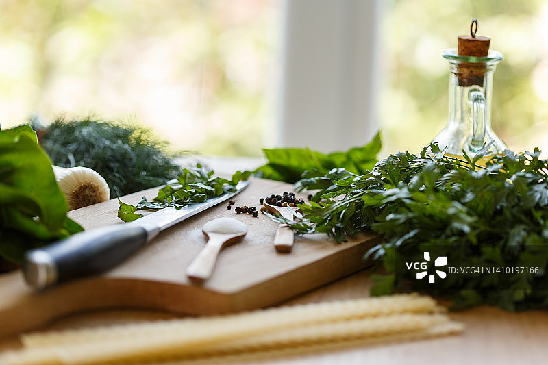 混合绿色香草，意大利面，胡椒和油摆放在厨房柜台上图片素材
