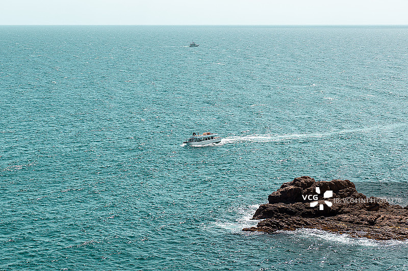 船只航行在海上附近的岩石形成的西班牙。阳光明媚的水上日子图片素材