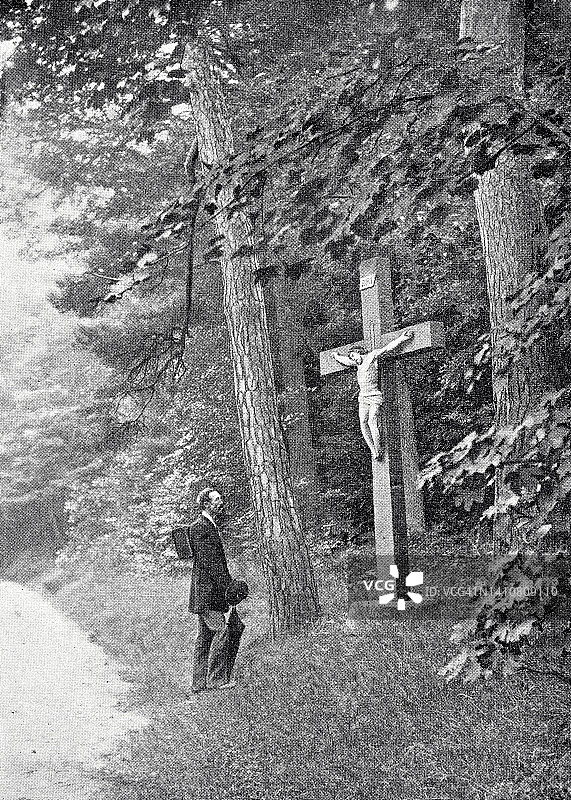 一个人站在森林边缘的十字架前祈祷图片素材