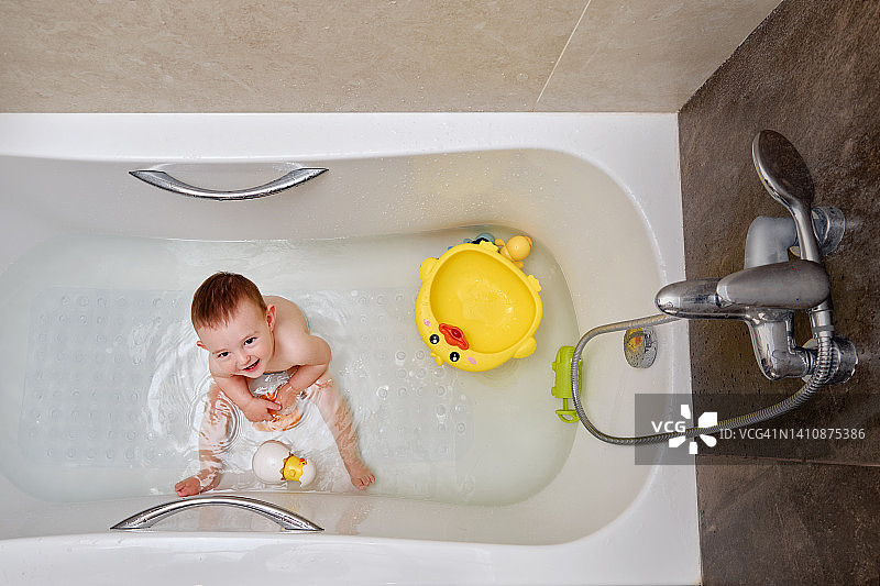 快乐的小男孩正在浴缸里玩玩具图片素材