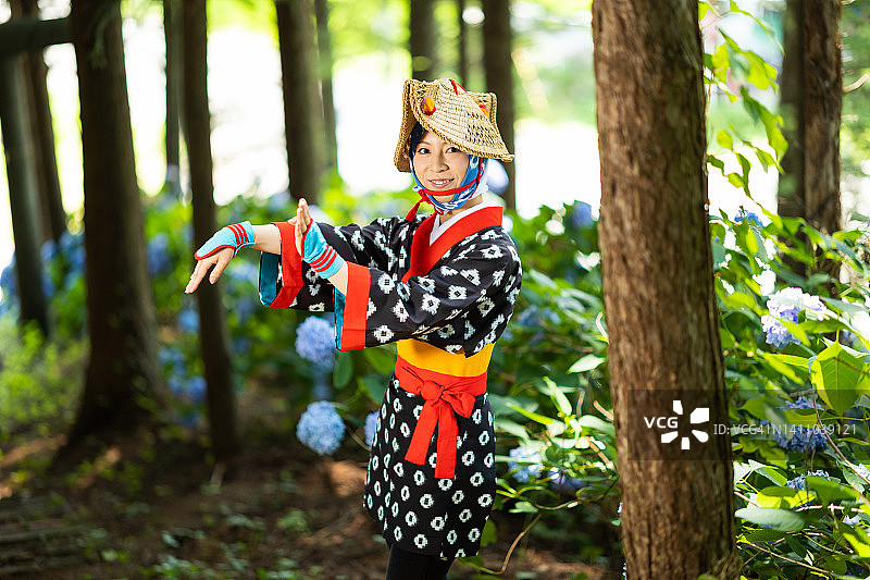 手持绣球花在山林中的日本女节日舞者图片素材