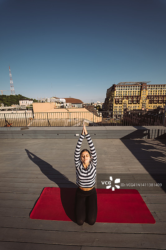 清晨，一名女子在屋顶上做瑜伽图片素材