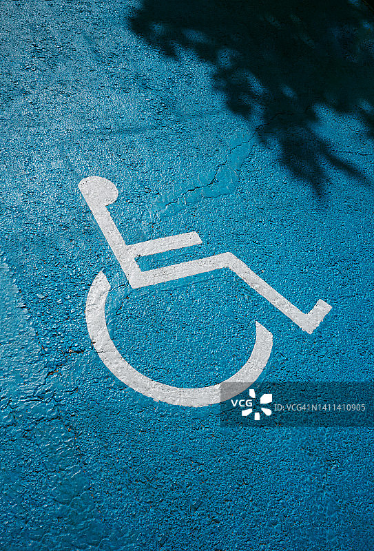 在公共停车场的地面上画着蓝色的残疾人停车标志。图片素材