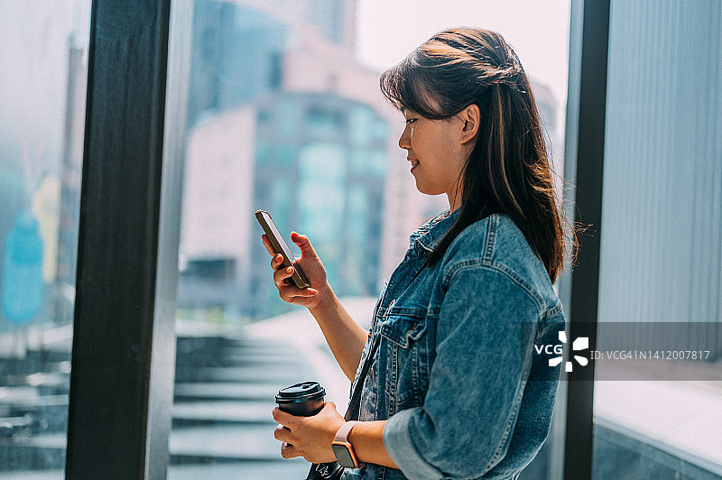 近距离观察年轻的亚洲女性在城市里用手机发短信和浏览社交媒体图片素材