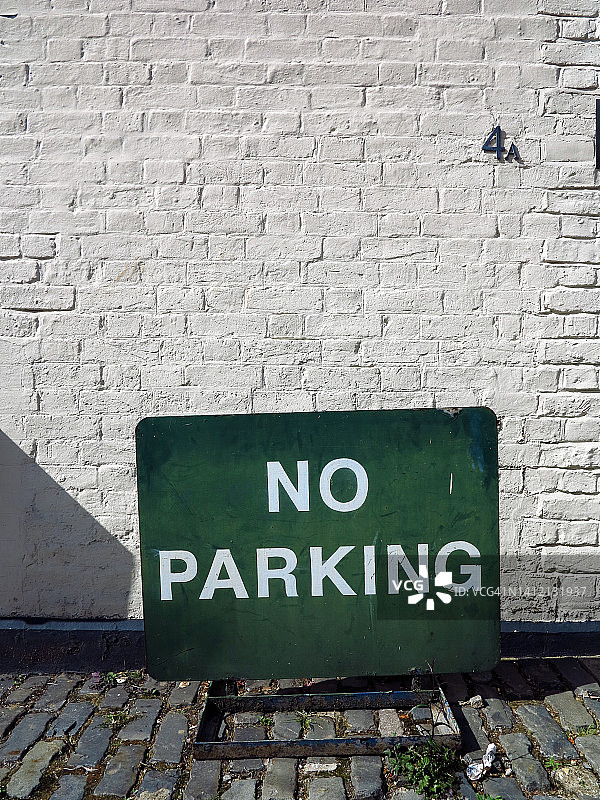 放置在地面上，在白砖墙前，一个古老的无街道停车标志，在英国伦敦，英国图片素材