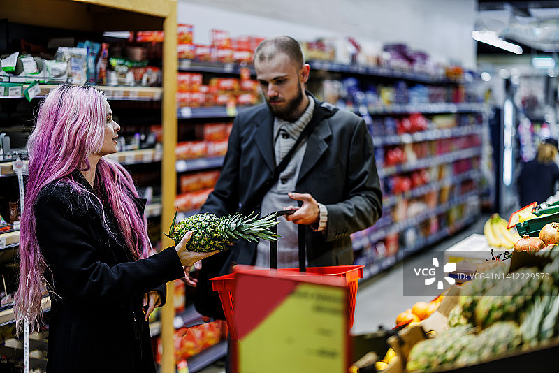 一对年轻夫妇在当地的市场商店买水果和蔬菜。图片素材